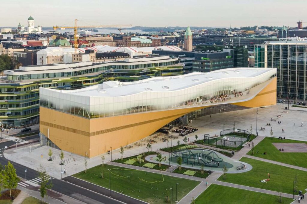 Exterior view of Central Library Oodi in Helsinki, showcasing its futuristic design and white wave-like structure.
