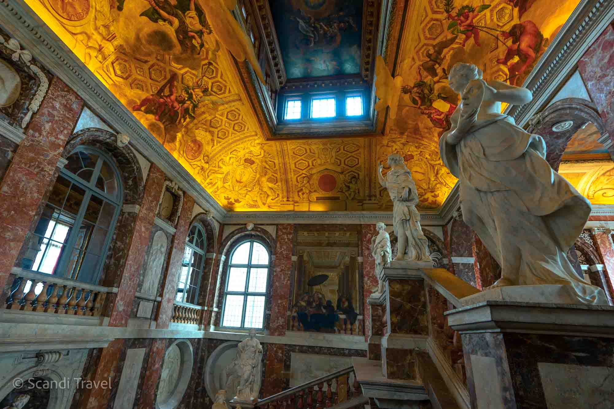 Interior view of Drottningholm Palace in Stockholm, featuring marble statues and ornate ceiling frescoes
