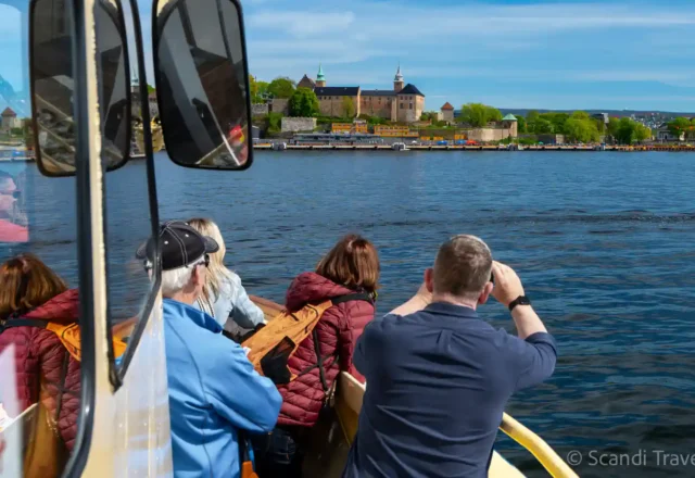Tourists on Scandi Travel boat tour in Oslo viewing Akershus Fortress across the Oslofjord