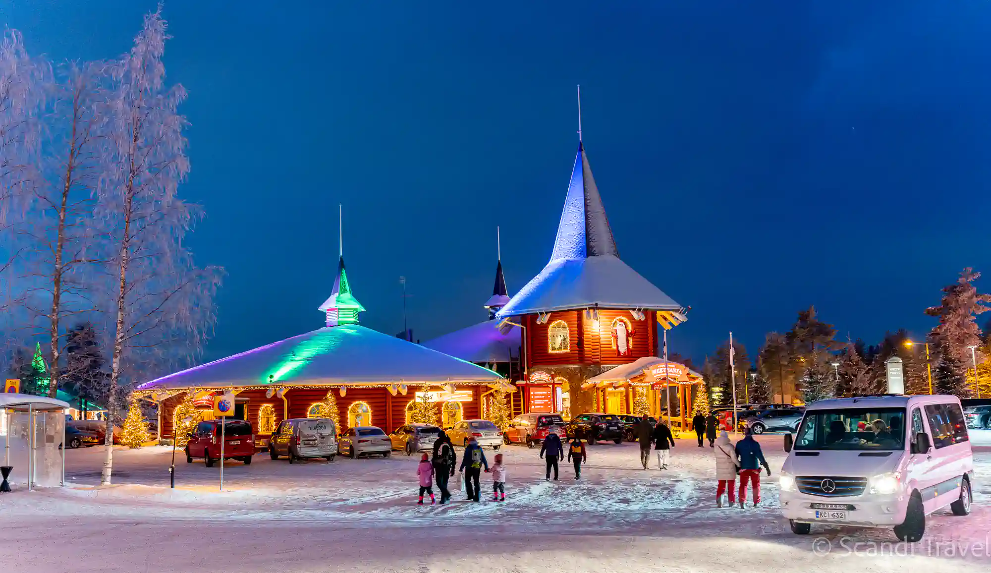 Santa Claus Village in Rovaniemi at blue hour, with the illuminated Meet Santa building and visitors in the snow, visited on the 7-day Lapland Northern Lights tour