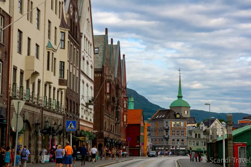 Historic Bryggen street in Bergen, Norway, with colorful wooden buildings and mountain backdrop