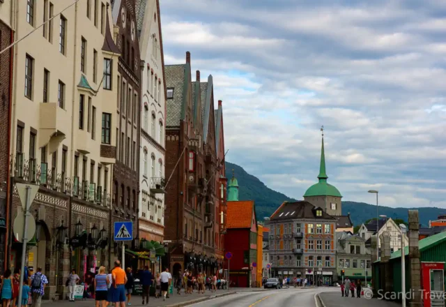 Historic Bryggen street in Bergen, Norway, with colorful wooden buildings and mountain backdrop
