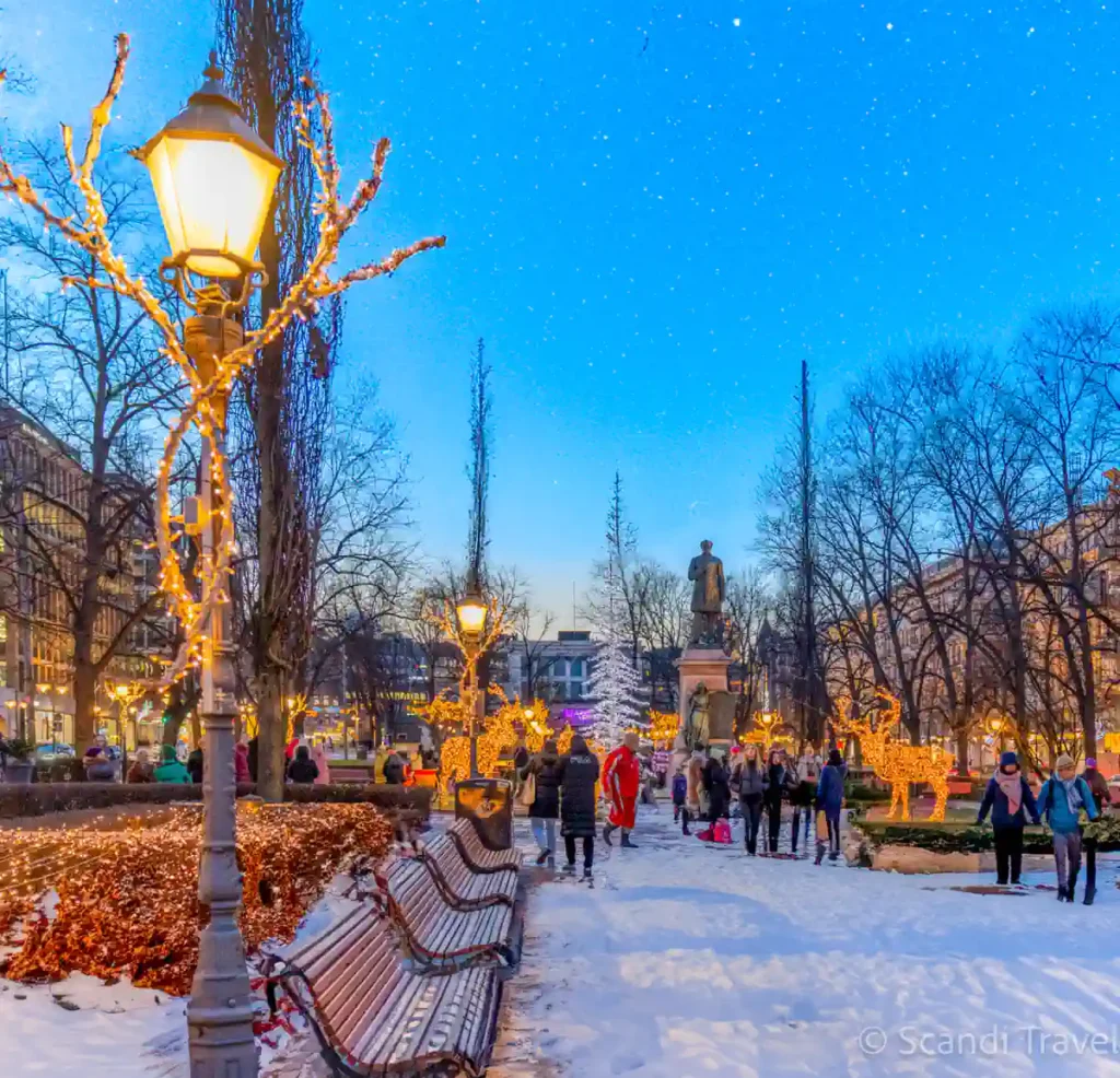 Winter evening at Esplanadi Park in Helsinki with festive Christmas lights and people enjoying the snowy scenery.