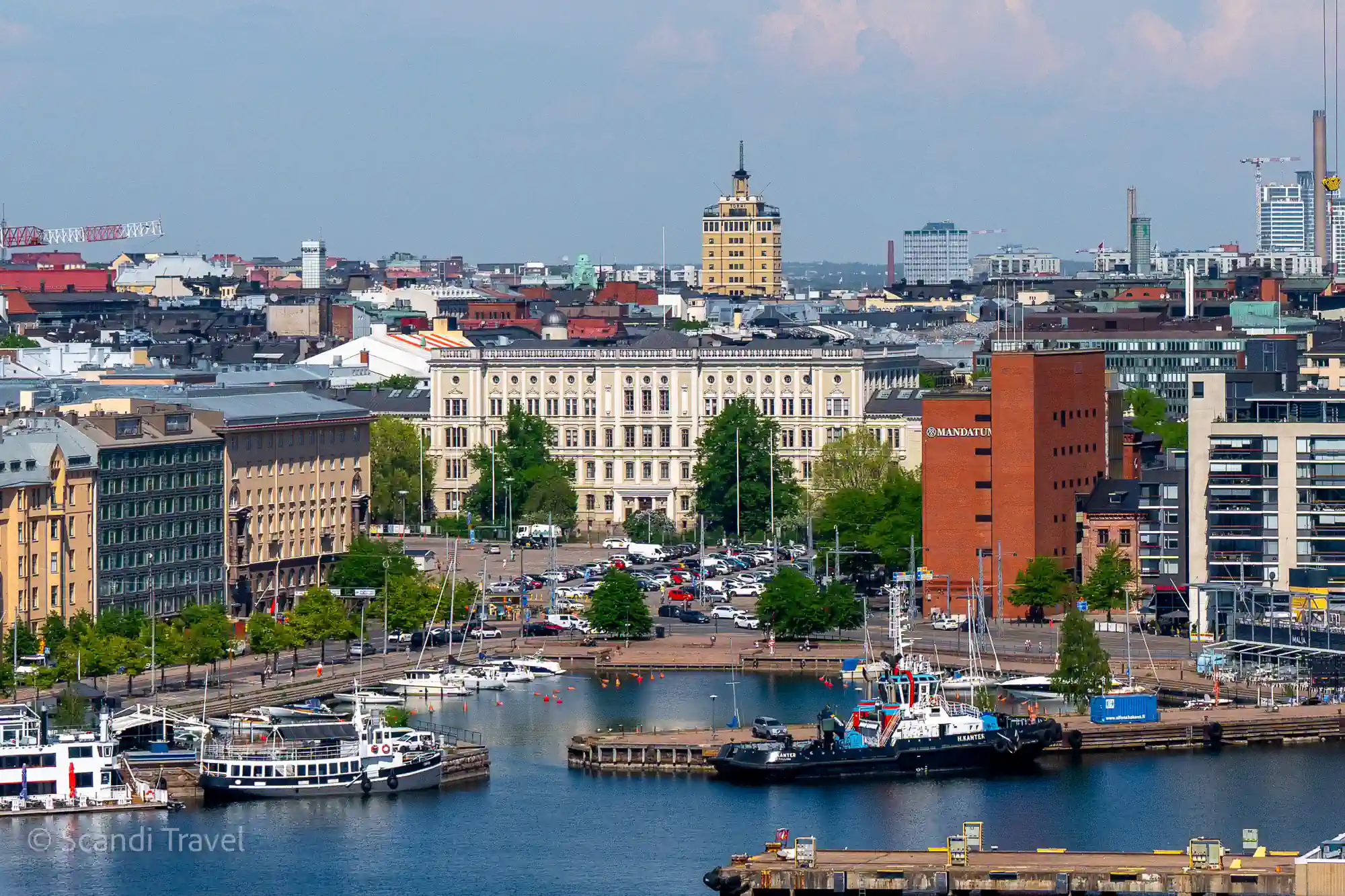 Central Helsinki seen from above the harbour on a summer day, with boats in the basin and the yellow tower of Hotel Torni on the skyline