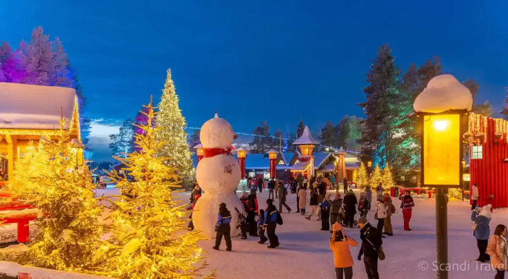 Visitors enjoying Santa Claus Village in Rovaniemi, Lapland, Finland during winter evening