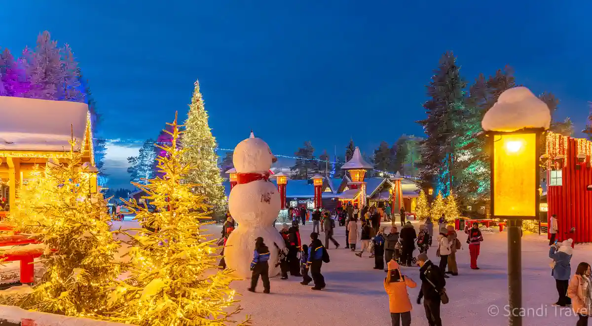Visitors enjoying Santa Claus Village in Rovaniemi, Lapland, Finland during winter evening