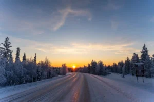 Sunset over a snowy forest road in Lapland during the Arctic Adventure tour through Finland and Norway