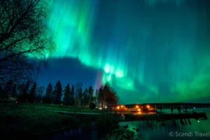 Vibrant green Northern Lights (Aurora Borealis) reflecting in a lake during an autumn tour in Finnish Lapland.