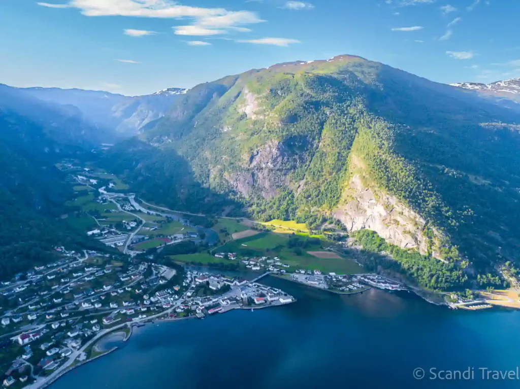 Aerial view of a fjord village on the Aurlandsfjord in Norway in summer, with steep green mountains and deep blue water, on a Scandi Travel tour