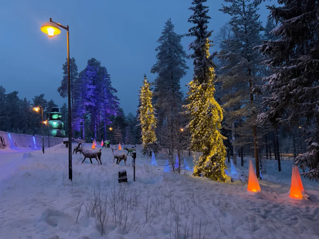 Snow-covered pine forest and frozen lake in Finnish Lapland at dusk, representing Scandi Travel's Lapland winter tour packages