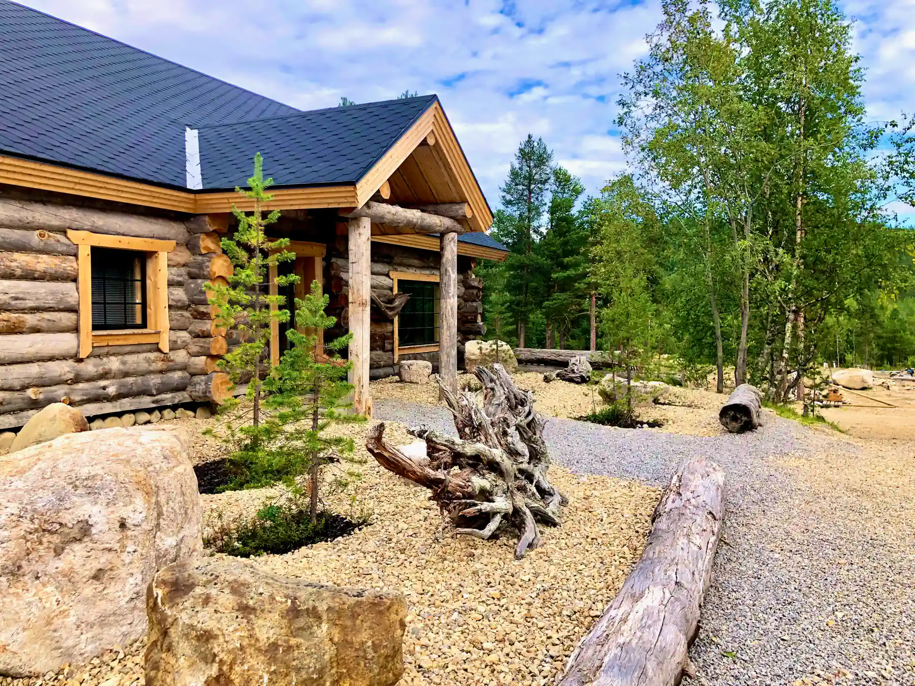Traditional log cabin exterior in Finnish Lapland surrounded by forest and a landscaped stone garden