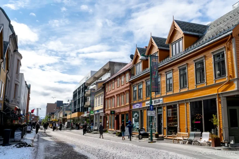 Historic wooden houses on Storgata, the main street of Tromsø, with a light dusting of snow on the pavement