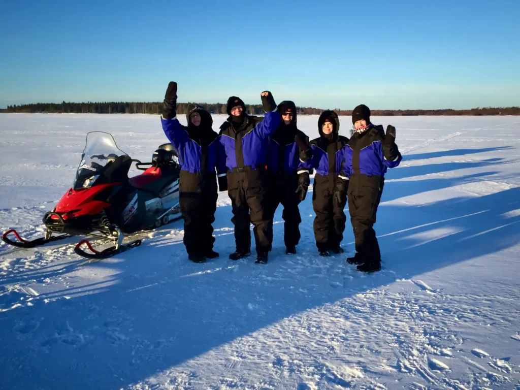 Part of the Scandi Travel team in snowmobile suits on the ice in Lapland