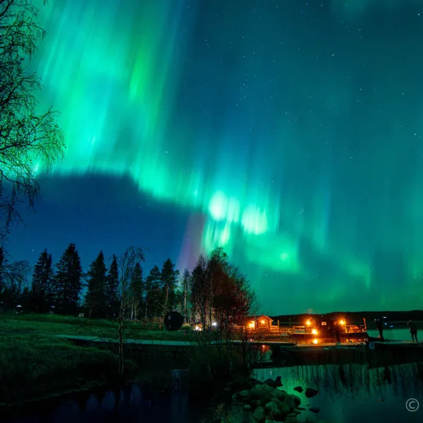 Vibrant green Northern Lights (Aurora Borealis) reflecting in a lake during an autumn tour in Finnish Lapland.